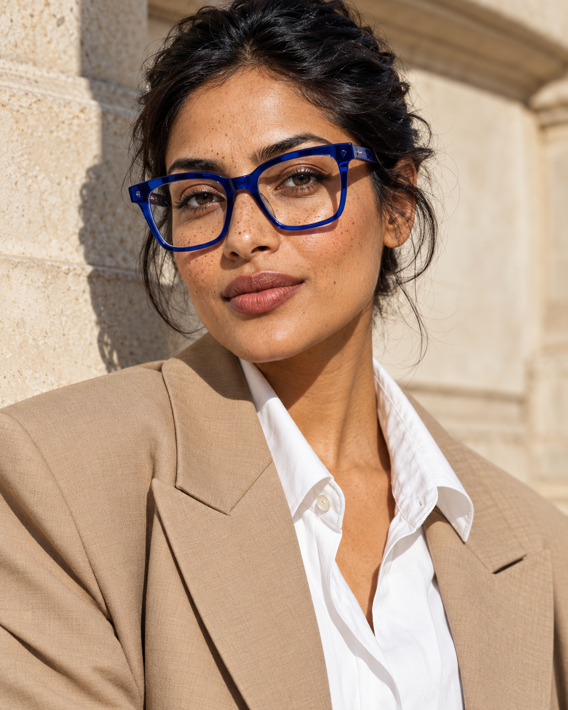 Woman wearing sculptural blue optical frames in warm sunlight